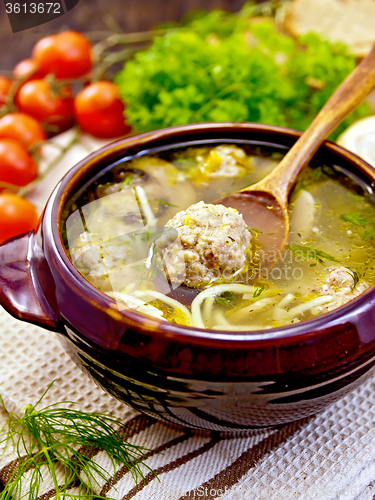 Image of Soup with meatballs and spoon in pottery on napkin