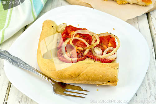 Image of Pie with onions and tomatoes in white plate on board