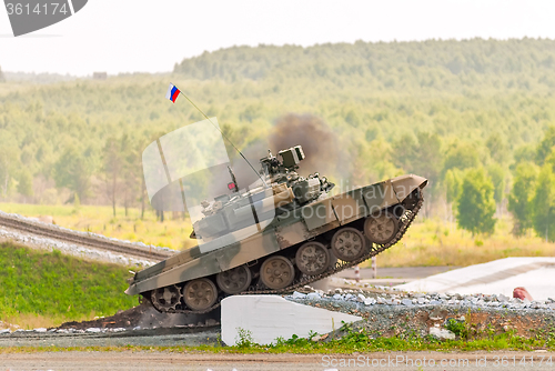 Image of Tank T-80 overcomes a high concrete obstacle