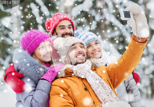Image of smiling friends with camera in winter forest