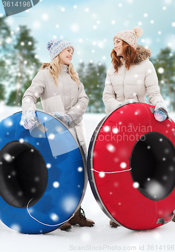 Image of happy girl friends with snow tubes outdoors