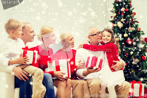 Image of smiling family with gifts hugging at home