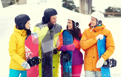 Image of happy friends in helmets with snowboards talking