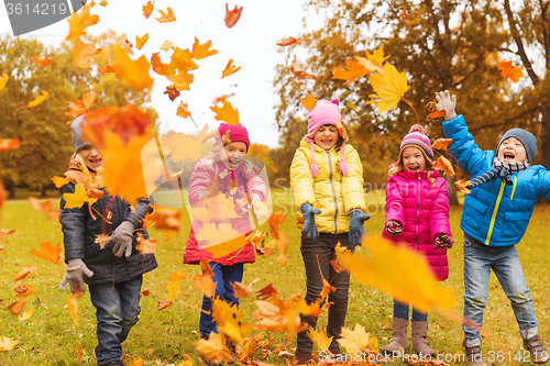 Image of happy children playing with autumn leaves in park