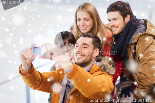 Image of happy friends with camera on skating rink