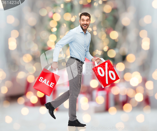 Image of man with shopping bags over christmas lights