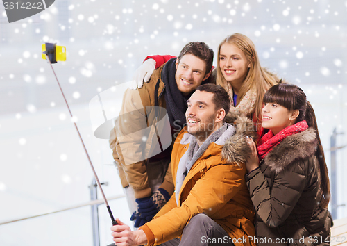 Image of happy friends with smartphone on skating rink