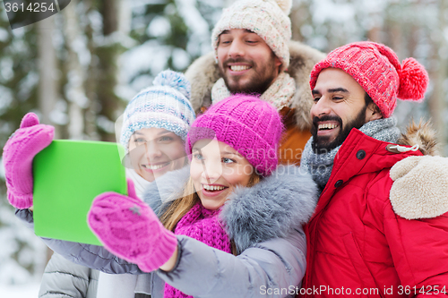 Image of smiling friends with tablet pc in winter forest
