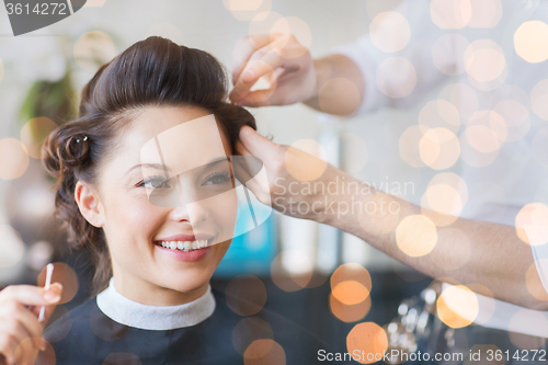 Image of happy woman with stylist making hairdo at salon