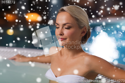 Image of happy woman sitting in jacuzzi at poolside