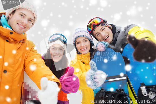 Image of happy friends with snowboards showing thumbs up