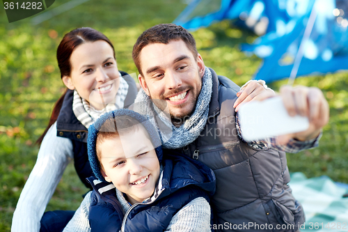 Image of family with smartphone taking selfie at campsite