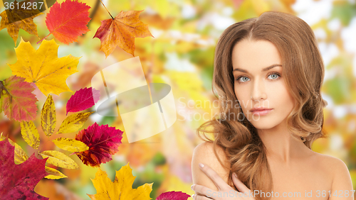 Image of beautiful young woman face over autumn leaves