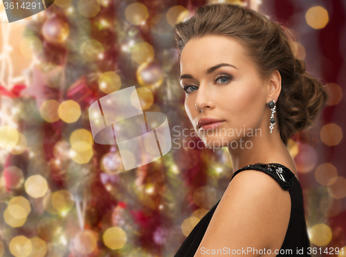 Image of beautiful woman wearing earrings over lights