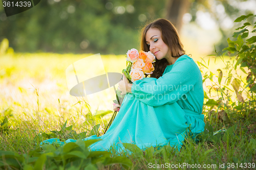 Image of Young girl smelling a bouquet of roses fragrance under the shadow of the trees in the sunny weather