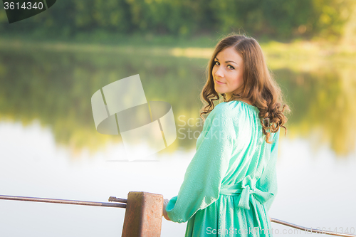 Image of A girl standing on a bridge over the river turned and looked into the frame