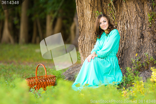 Image of A girl in a long dress sat by a tree, next to put the cart