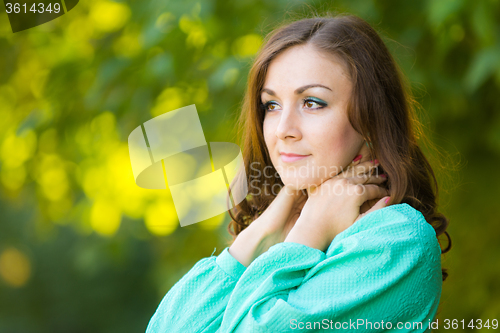 Image of Portrait of a girl hugging his neck on a background of green foliage