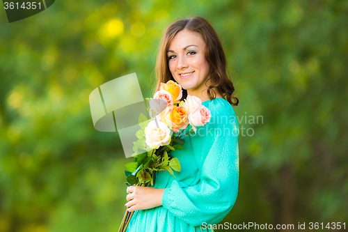 Image of Portrait of a girl with a bouquet of roses on the background blurred foliage