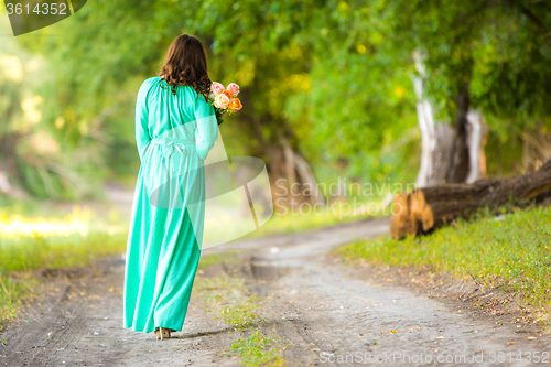 Image of A girl in a long dress walking along the road with a basket in the hands of