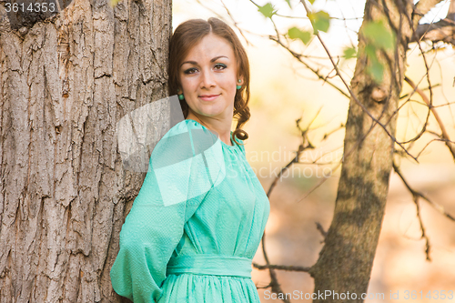 Image of Portrait of a girl leaning on a tree in the woods