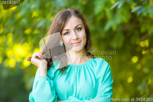 Image of The waist of a beautiful girl in a dress on a background of blurred green foliage