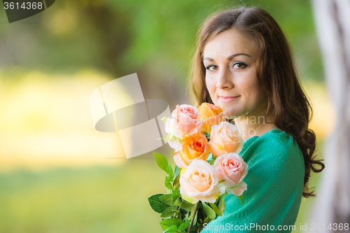 Image of Portrait of a girl with a bouquet of roses on a background blur forest