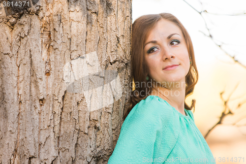 Image of Portrait of a girl leaning against a tree