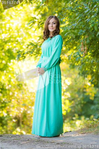 Image of A girl in a long dress against a background of blurred forest