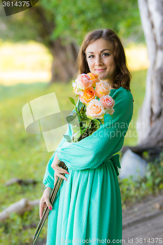 Image of Portrait of a girl with a bouquet of roses walking in the woods