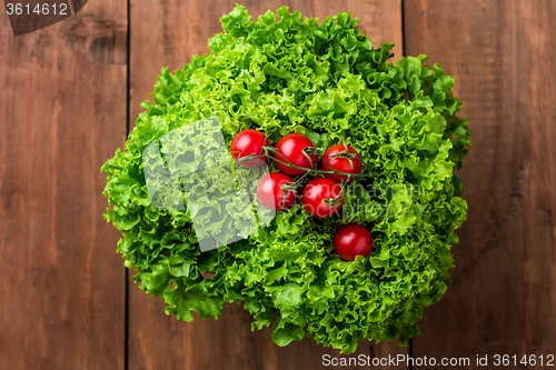 Image of lettuce salad and cherry tomatoes on a wood background