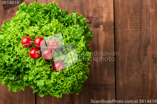 Image of lettuce salad and cherry tomatoes on a wood background