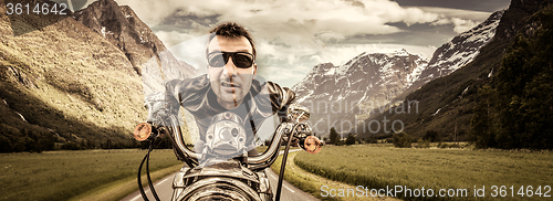 Image of Funny Biker in sunglasses and leather jacket racing on mountain 