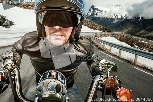 Image of Biker in helmet and leather jacket racing on mountain serpentine