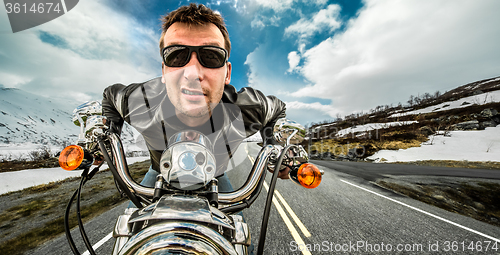 Image of Funny Biker in sunglasses and leather jacket racing on mountain 