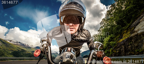 Image of Biker in helmet and leather jacket racing on mountain serpentine