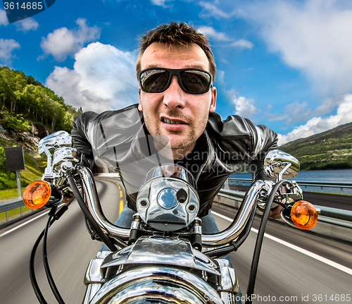 Image of Funny Biker in sunglasses and leather jacket racing on mountain 