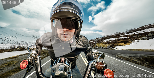 Image of Biker in helmet and leather jacket racing on mountain serpentine