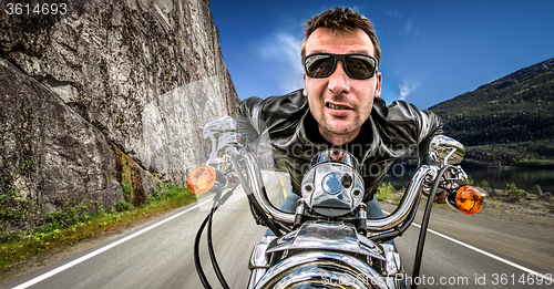 Image of Funny Biker in sunglasses and leather jacket racing on mountain 