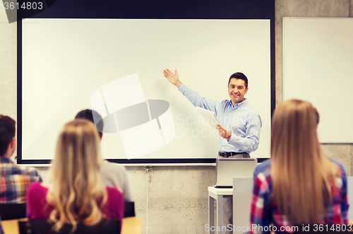 Image of group of students and smiling teacher with notepad