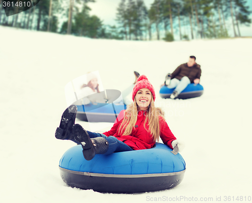 Image of group of happy friends sliding down on snow tubes