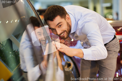 Image of happy man touching car in auto show or salon