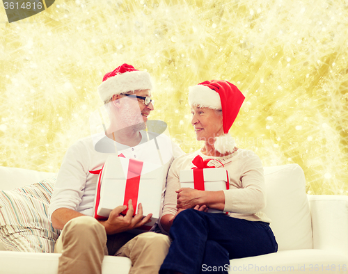 Image of happy senior couple in santa hats with gift boxes