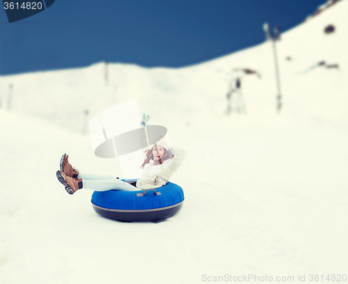 Image of happy teenage girl sliding down on snow tube