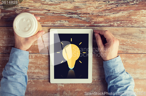 Image of close up of hands with ligting bulb on tablet pc