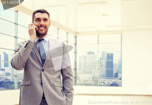 Image of happy young businessman calling on smartphone