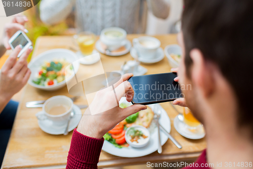 Image of friends with smartphones taking picture of food