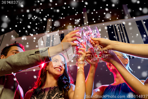 Image of smiling friends with glasses of champagne in club