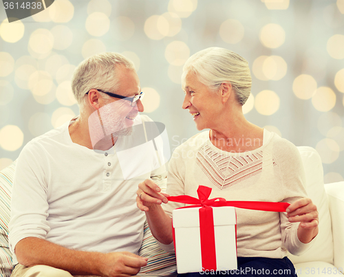 Image of happy senior couple with gift box at home