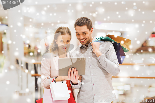 Image of couple with tablet pc and shopping bags in mall